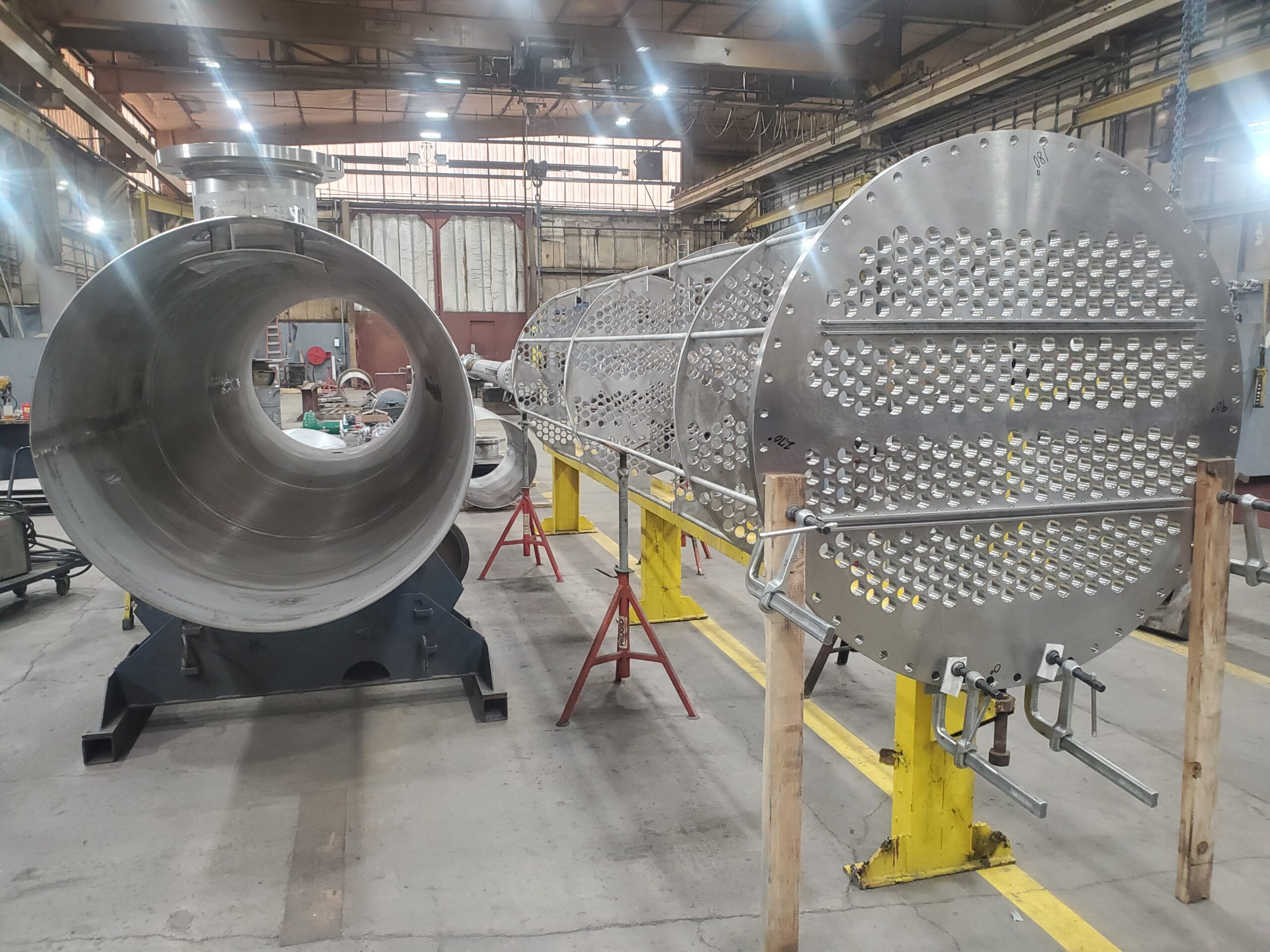 Stainless shell-and-tube heat exchanger shell and drilled tubesheet under assembly in the Harris Thermal shop